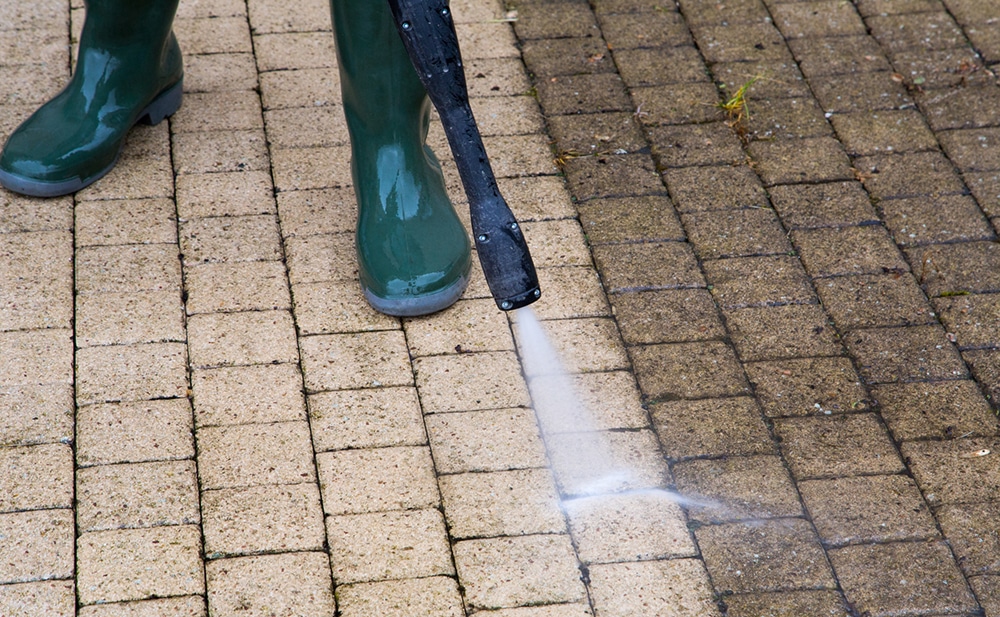 Technician pressure washing stained concrete with controlled equipment and precise surface technique