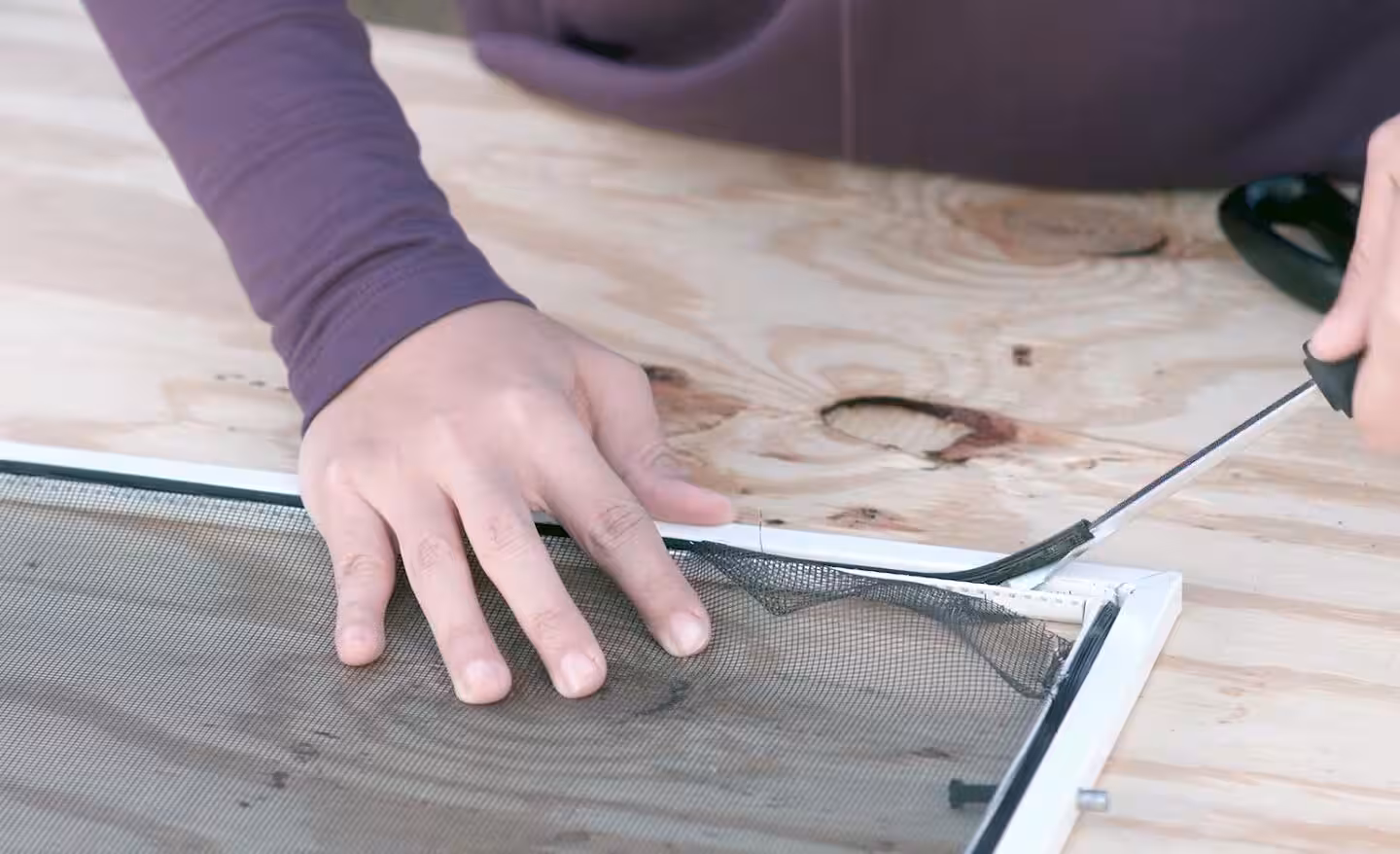 Experienced technician carefully patching damaged screen mesh with precise repair tools